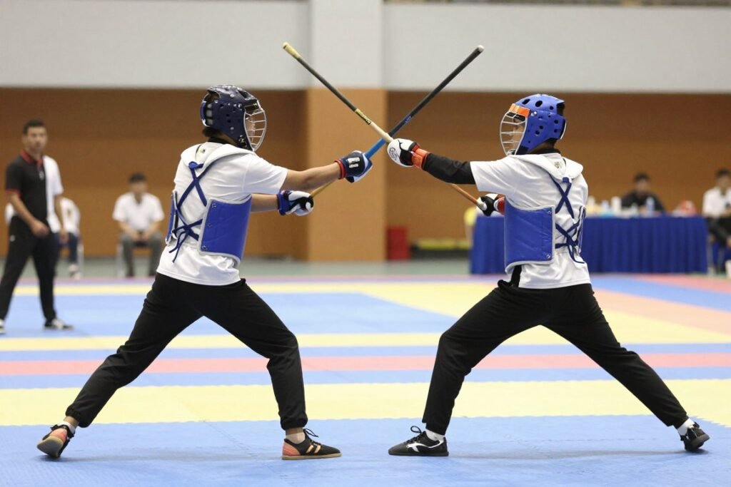 Athletes competing in an inter-varsity Gatka stick sparring match on a padded court
